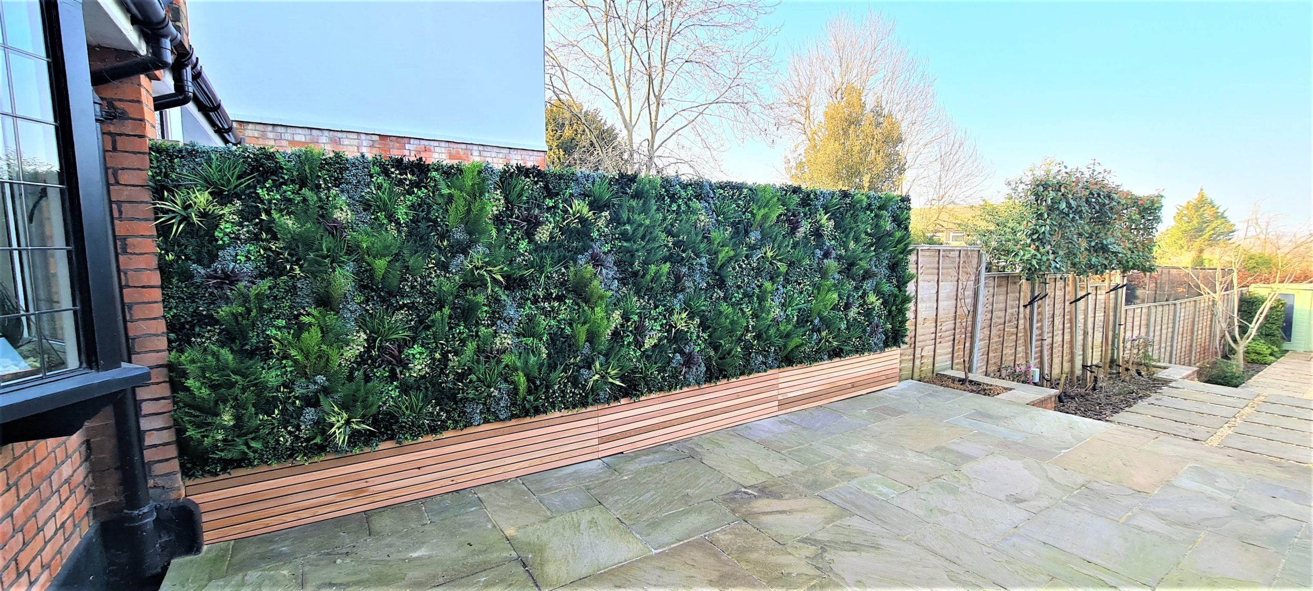 an artificial green wall installation on a fence by Vistafolia