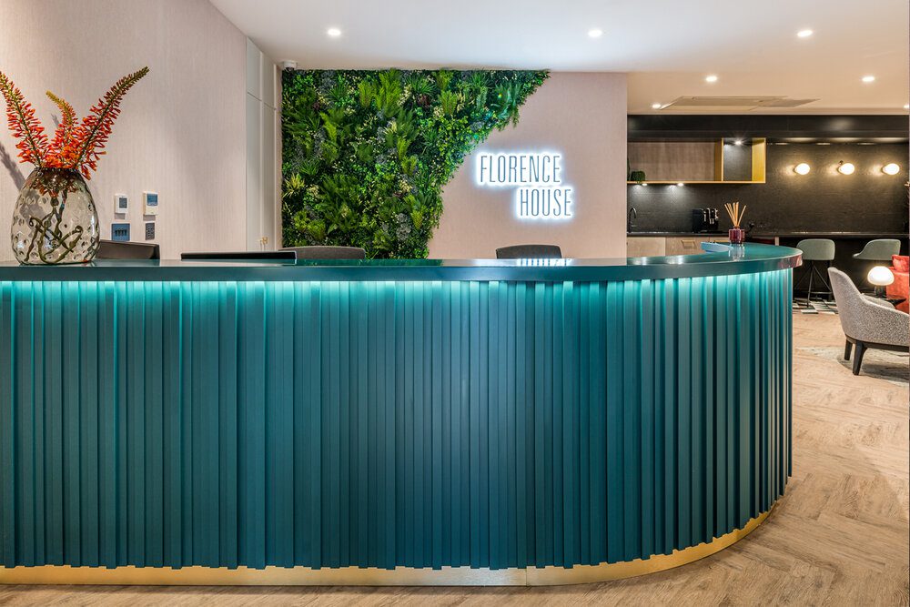 Planted green wall behind a reception desk in an apartment block.