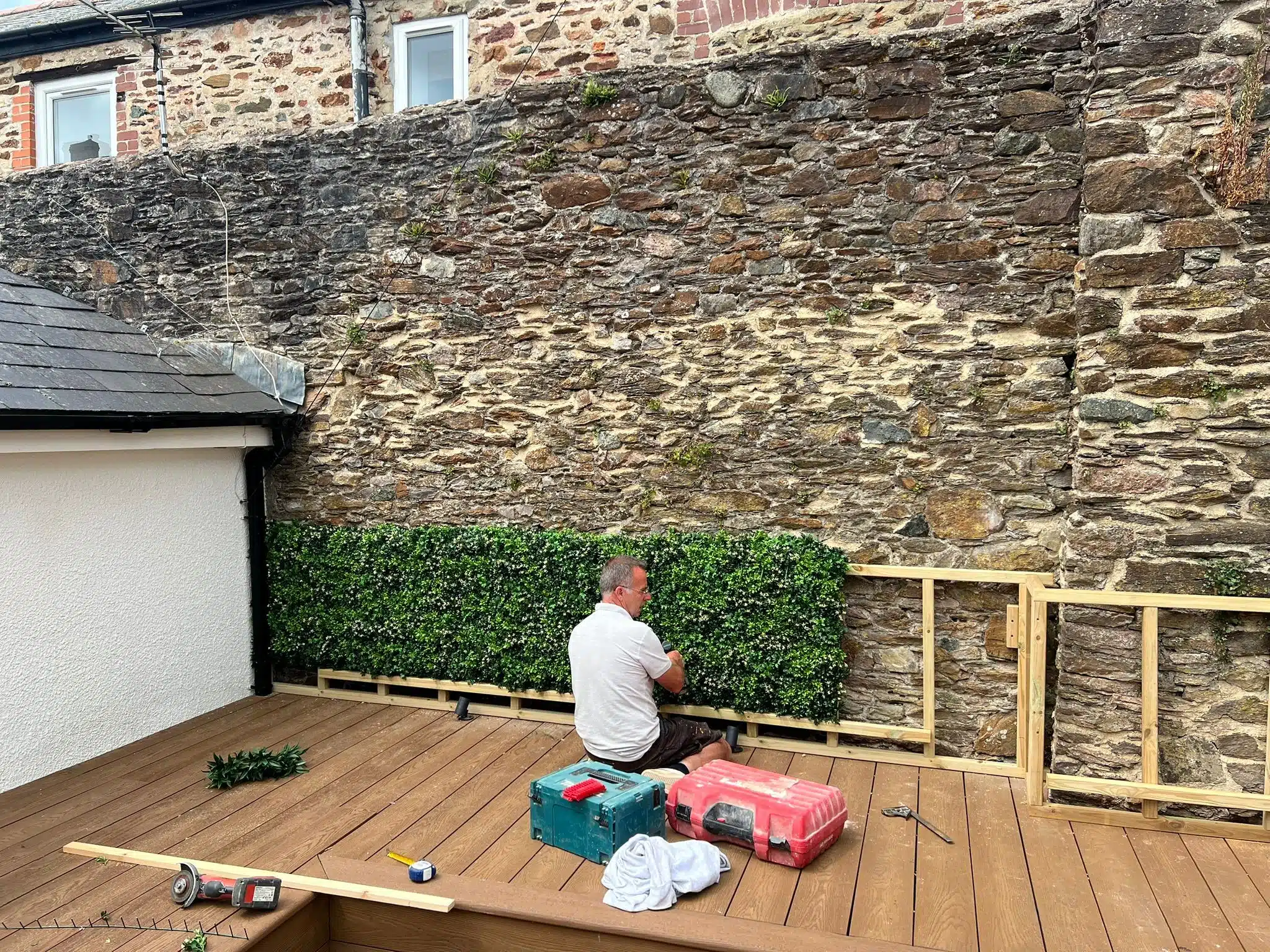 A Vistafolia operative installing a custom artificial hedge in a garden in Cornwall