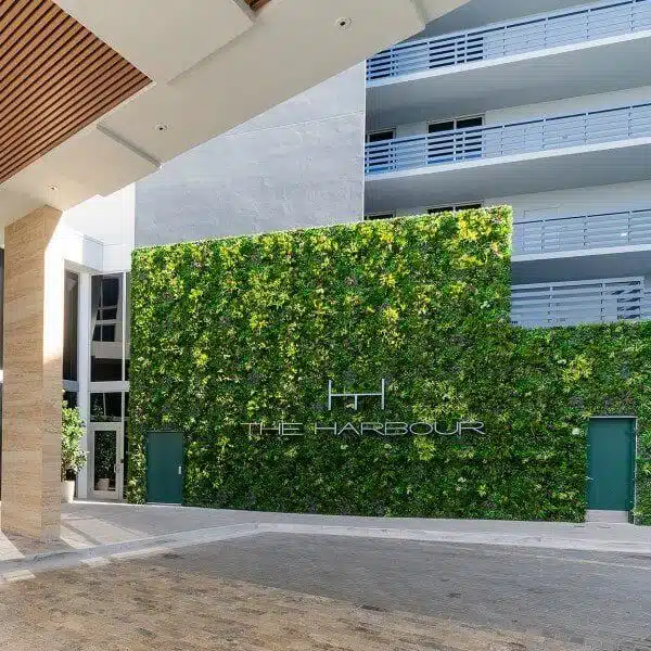 Entrance to The Harbour in Miami, Florida, showcases a large-scale green wall installation on a modern building. The lush vertical garden enhances the sleek lines and balconies of the facade, creating a contemporary and inviting appearance.