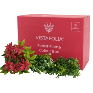 A pink box labeled Forest Flame Colour Box is surrounded by artificial plants with red and green leaves.