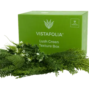 A green container labeled Lush Green Texture Box showcasing assorted artificial greenery and plants, including ferns and small white flowers, displayed in front of it.
