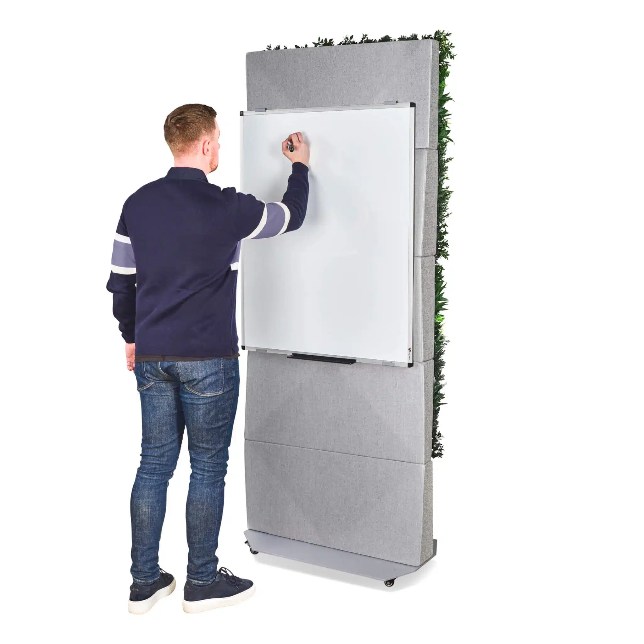 Someone wearing a navy and white sweater with jeans is writing on a whiteboard mounted to a tall, gray, mobile Modular Green Wall Partition. The panel has greenery on one side and wheels for easy mobility.