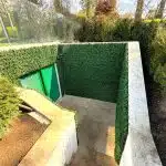 A green wall installation featuring artificial boxwood panels