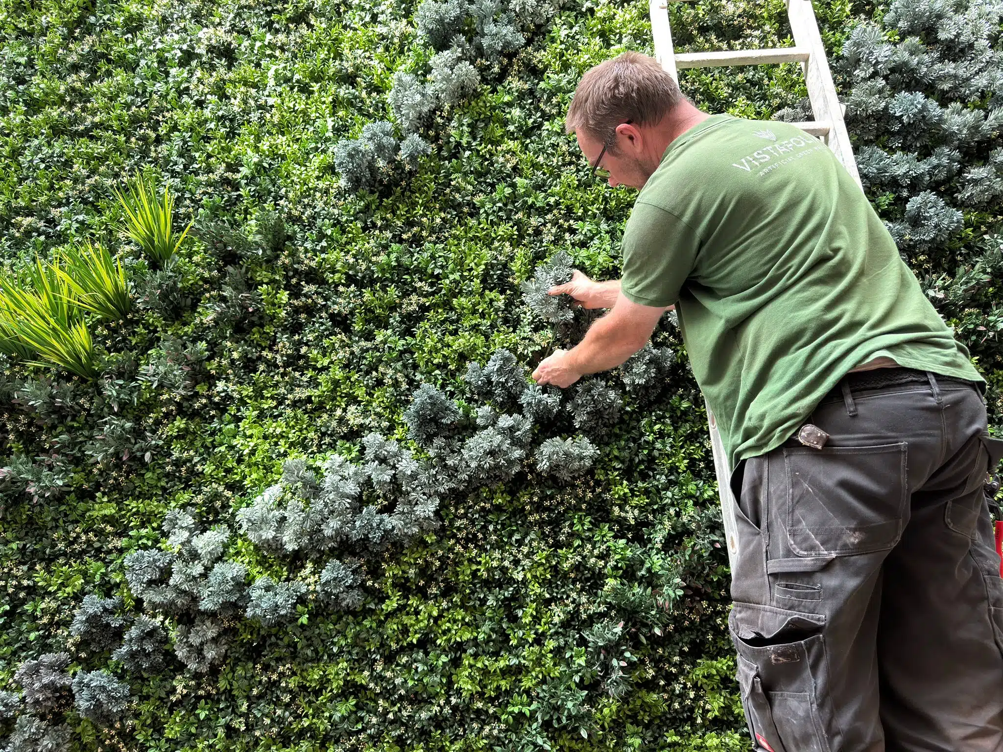 A Vistafolia operative installing a bespoke, custom artificial green wall in a garden