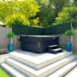 un paravent en buis artificiel au-dessus d'un jacuzzi dans un jardin