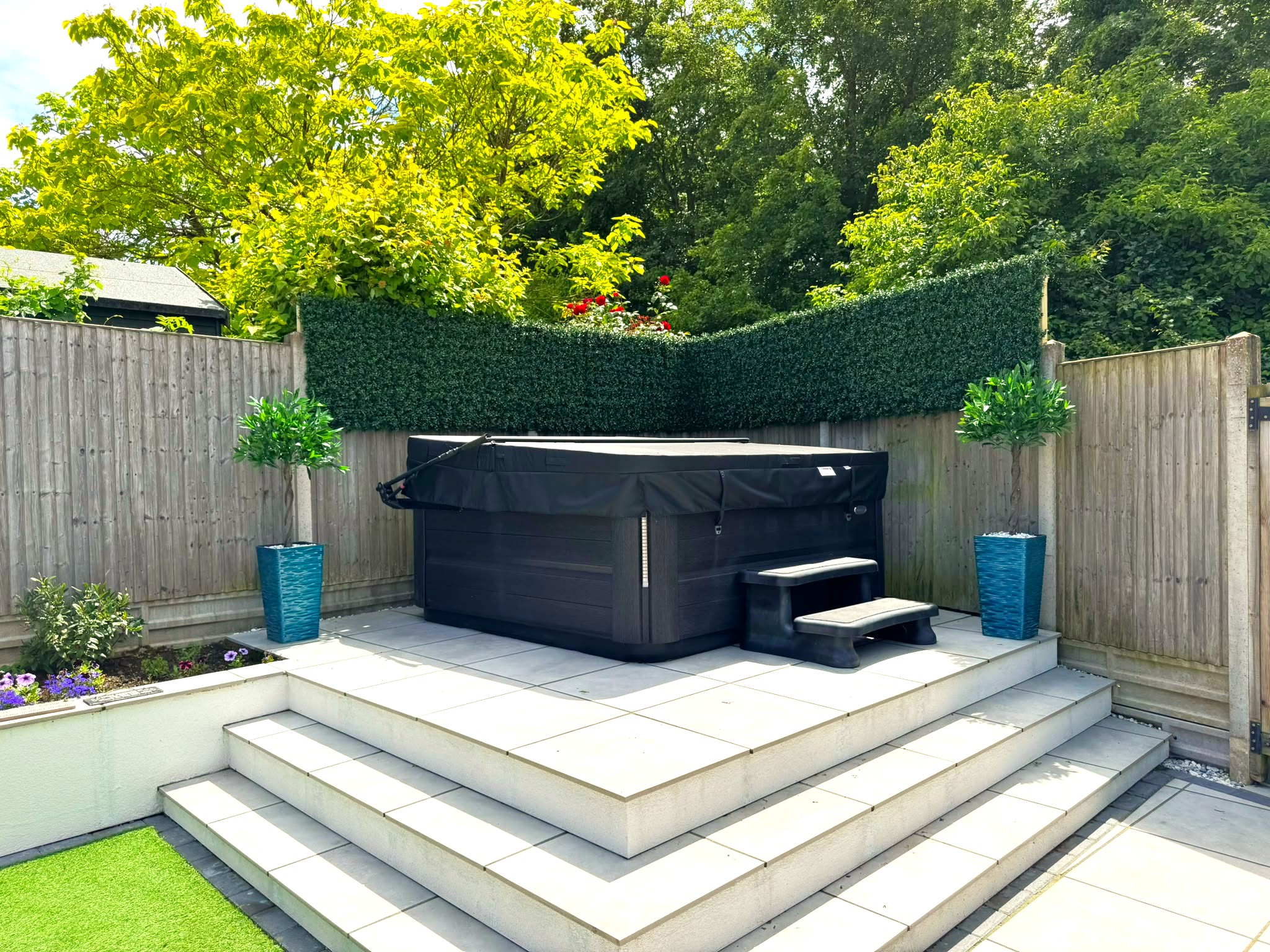 un paravent en buis artificiel au-dessus d'un jacuzzi dans un jardin