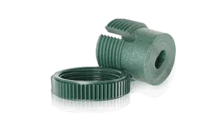 A green plastic fitting for the Green Wall Fixing System features a threaded cap. An upright piece reveals its hollow interior, while the cap rests nearby. The fitting has ridged sections for a secure grip.