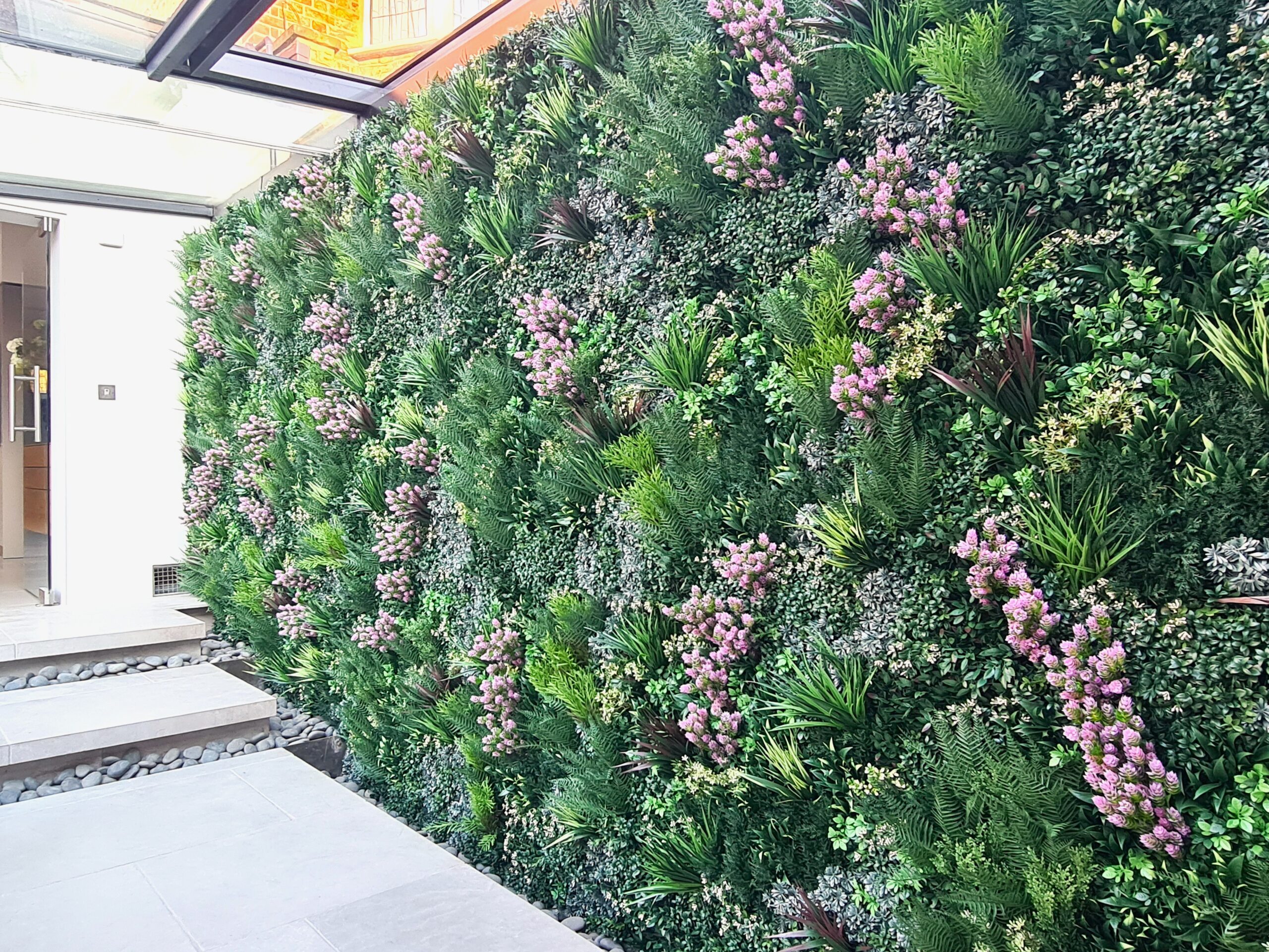 installation d'un mur végétal avec des fleurs roses, nécessitant peu d'entretien