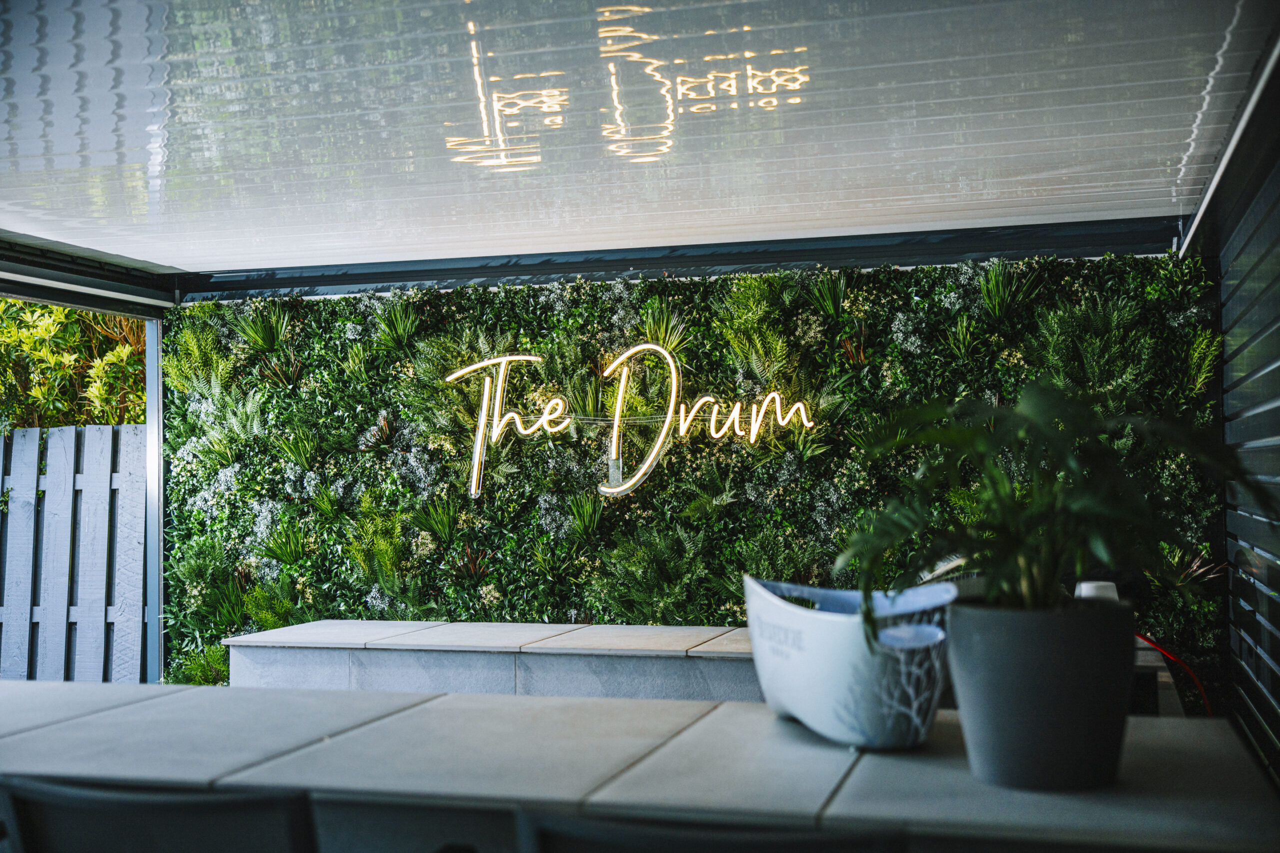 A green wall installation in an outdoor kitchen with a logo on it