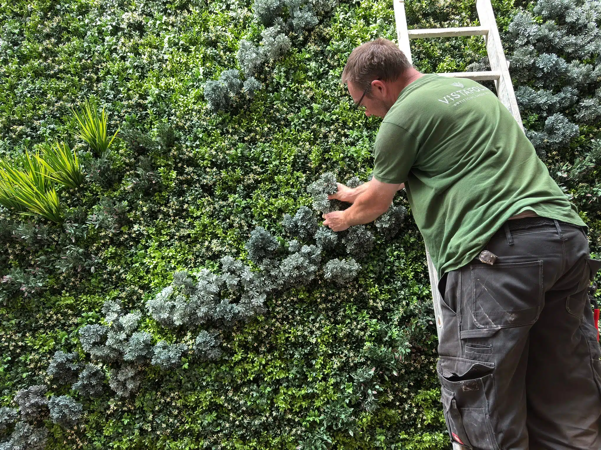a man installing an imitation fake moss wall in a lightwell in London