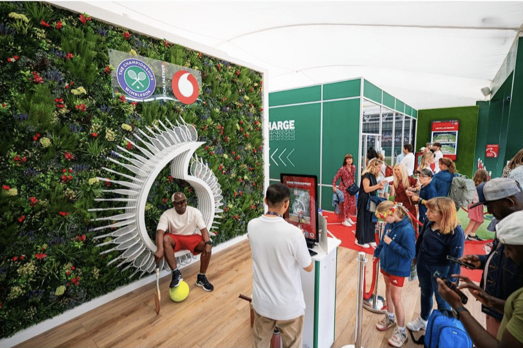 An artificial green wall with a sign installed on top for Vodafone at Wimbledon Tennis Championships