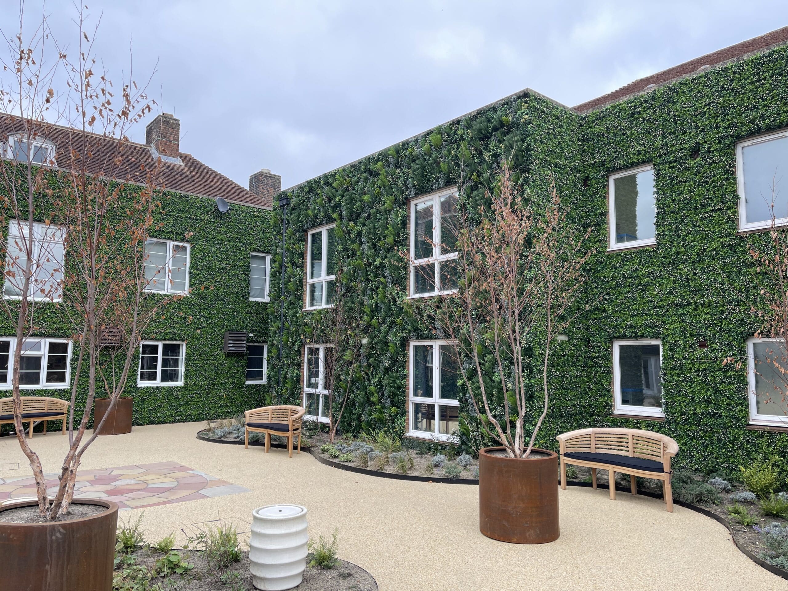 a commercial grade artificial greenery wall installed in a courtyard of a rehabilitation facility
